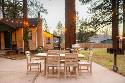 a wooden table with chairs and a grill in a yard at Lakewood Cabins in Big Bear Lake