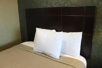 a bed with white pillows and a brown headboard at Crystal Inn Suites & Spas in Inglewood