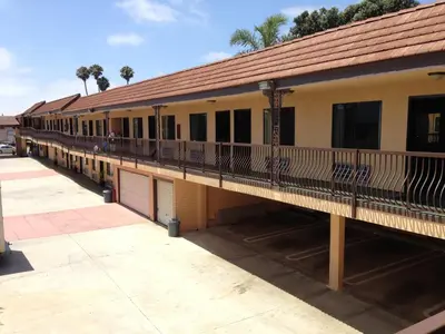 a building with a balcony and a building with palm trees at Del Amo Inn in Torrance