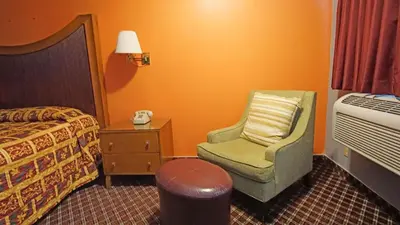 a hotel room with a bed and a chair and a lamp at Los Angeles Inn & Suites - LAX in Los Angeles