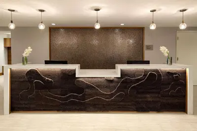 a reception desk in a lobby with a large wall at Redondo Beach Hotel, Tapestry Collection by Hilton in Redondo Beach