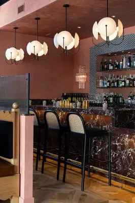 a bar in a restaurant with black chairs and lights at Short Stories Hotel Near The Grove in Los Angeles
