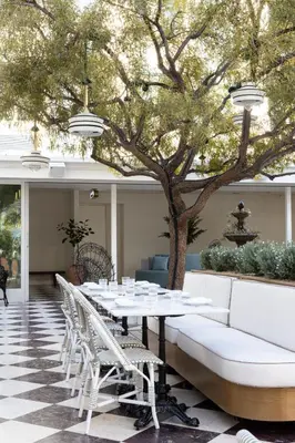 a table and chairs in a patio with a tree at Short Stories Hotel Near The Grove in Los Angeles