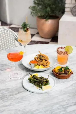a table with two plates of food and a drink at Short Stories Hotel Near The Grove in Los Angeles