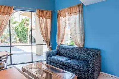 a blue living room with a blue couch and a glass table at Howard Johnson by Wyndham Norco in Norco