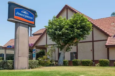 a sign in front of a building with a tree at Howard Johnson by Wyndham Norco in Norco