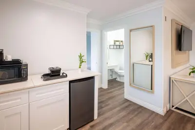 a white kitchen with a sink and a microwave at Ramada by Wyndham Redondo Beach in Redondo Beach