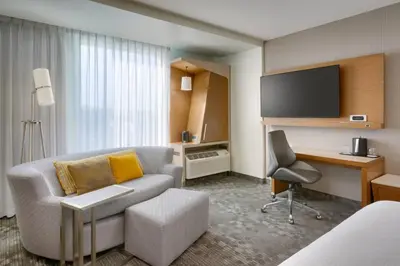 a hotel room with a couch and a desk at Courtyard by Marriott Los Angeles LAX/Hawthorne in Hawthorne