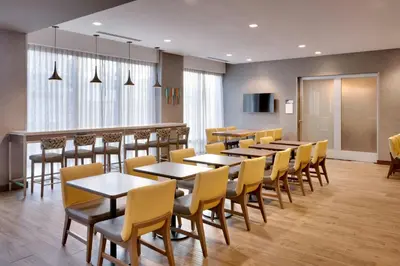 a dining room with tables and yellow chairs at TownePlace Suites by Marriott Los Angeles LAX/Hawthorne in Hawthorne
