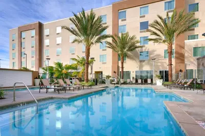 a pool with palm trees in front of a hotel at TownePlace Suites by Marriott Los Angeles LAX/Hawthorne in Hawthorne