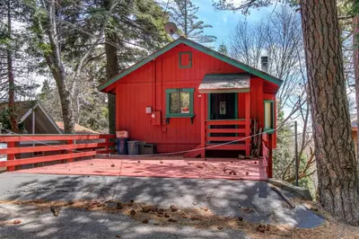 a red house with a deck in the woods at Victoria Court Vacation in Lake Arrowhead