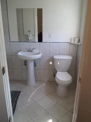 a bathroom with a toilet and a sink at New Kansan Motel in Rancho Cucamonga