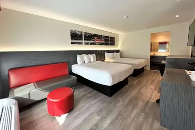 a hotel room with two beds and a red chair at Ramada by Wyndham Anaheim Convention Center in Anaheim