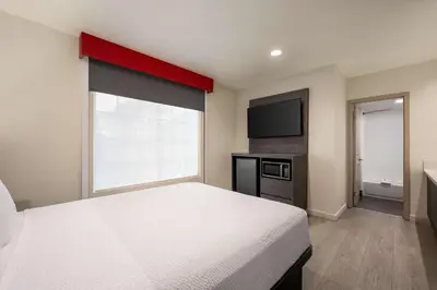 a bedroom with a white bed and a large window at Ramada by Wyndham Anaheim Convention Center in Anaheim