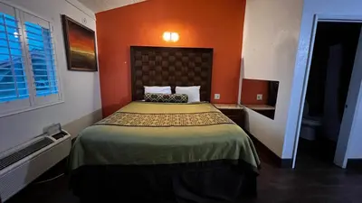 a bedroom with a bed with an orange wall at New American Inn & Suites in Anaheim