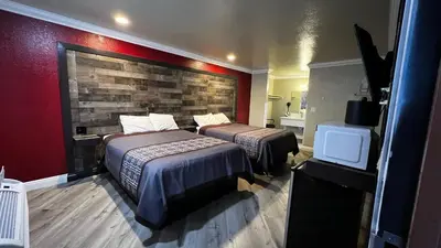 a hotel room with two beds and a brick wall at New American Inn & Suites in Anaheim