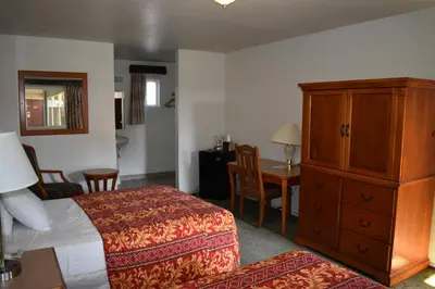 a hotel room with a bed and a cabinet and a table at Valley Hotel in Rosemead