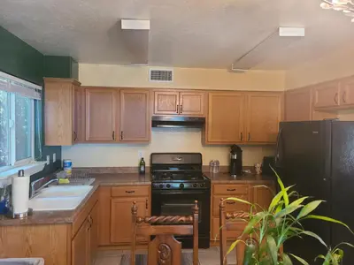 a kitchen with wooden cabinets and a black stove top oven at Sacred Mtn River Suites in Kernville