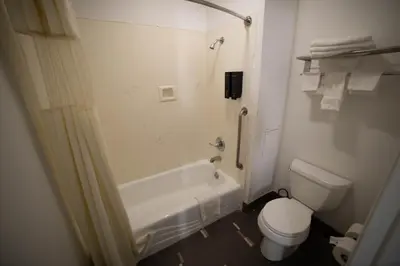 a bathroom with a toilet and a tub and a sink at Mid City Inn & Suites Pico Rivera in Pico Rivera