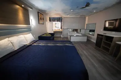 a hotel room with a large bed and a kitchen at Mid City Inn & Suites Pico Rivera in Pico Rivera