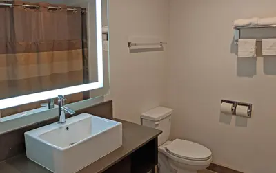 a bathroom with a sink and a toilet and a window at Epic Hotel in Pico Rivera