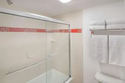 a bathroom with a glass shower and white towels at Best Western Plus Raffles Inn & Suites in Anaheim