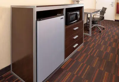 a kitchen with a refrigerator and a desk with a microwave at Best Western Plus Raffles Inn & Suites in Anaheim