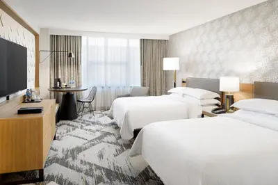 a hotel room with two beds and a flat screen tv at Sheraton Cerritos in Buena Park