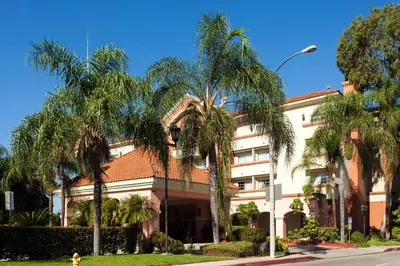 a building with palm trees in front of it at Park Suites Hotel in South El Monte