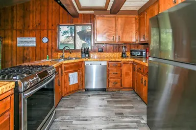 a kitchen with wooden cabinets and a stainless steel refrigerator at Lakeview Fishing House-121 by Big Bear Vacations in Big Bear Lake