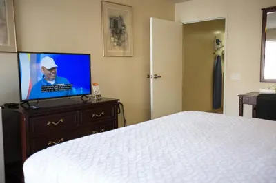 a bedroom with a bed and a flat screen tv at Queens Inn Anaheim in Anaheim