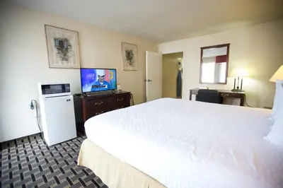 a hotel room with a large white bed and a tv at Queens Inn Anaheim in Anaheim