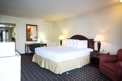 a hotel room with a large bed and a chair at Queens Inn Anaheim in Anaheim