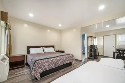 a bedroom with two beds and a table and chairs at 24 Hours Motel in Los Angeles