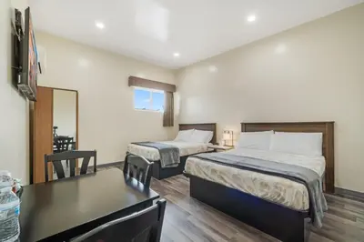 a bedroom with two beds and a table and a desk at 24 Hours Motel in Los Angeles