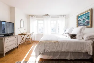 a white bedroom with a bed and a television at The Venice Beach House in Los Angeles