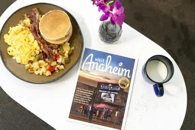 a table with a plate of food and a magazine at ALO Hotel by Ayres, Orange in Anaheim