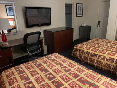 a hotel room with two beds and a desk and a television at Grand Inn in Fullerton