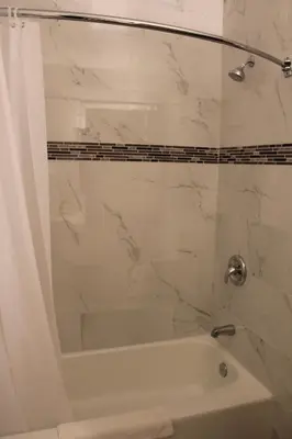 a bathroom with a tub and a shower with a glass door at Grand Inn in Fullerton