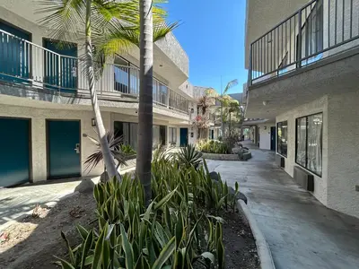 a building with palm trees next to a sidewalk at Studio 6 Suites Gardena, CA in Gardena