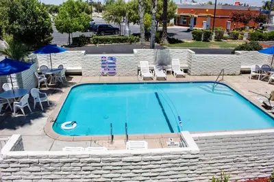 a large blue swimming pool with chairs and umbrellas at Motel 6-Bakersfield, CA - South in Bakersfield