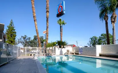 a swimming pool with palm trees and a basketball hoop at Motel 6-Bakersfield, CA - South in Bakersfield