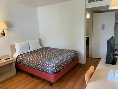 a small bed in a room with a desk at Vagabond Inn Sylmar in Sylmar