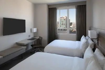 a hotel room with two beds and a flat screen tv at AC Hotel by Marriott Beverly Hills in Los Angeles
