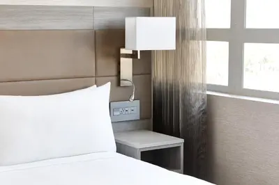 a bedroom with a bed and a lamp next to a window at AC Hotel by Marriott Beverly Hills in Los Angeles