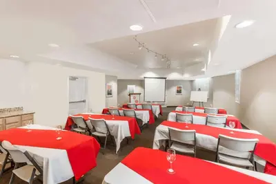 a conference room with red and white tables and chairs at Hawthorn Suites in Victorville