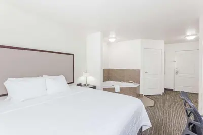 a bedroom with a white bed and a bathroom at Hawthorn Suites in Victorville