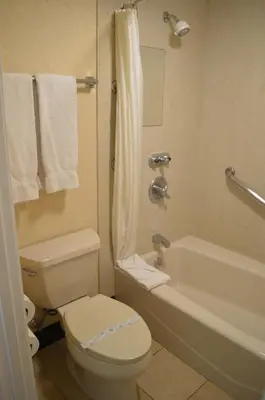 a bathroom with a toilet and a tub and a sink at Ontario Airport Inn in Ontario