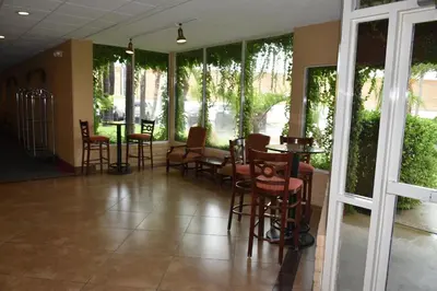 a lobby with chairs and tables and windows at Ontario Airport Inn in Ontario