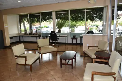 a waiting room with chairs and tables and windows at Ontario Airport Inn in Ontario